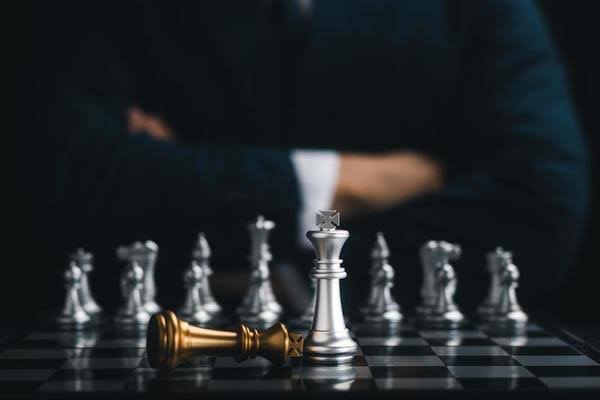 Chess board with a fallen gold king piece — representing the brutal reality of workplace competition and corporate strategy