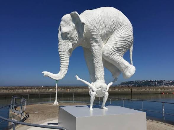 Sculpture of a small figure supporting an enormous elephant on their back — symbolising the crushing weight of carrying disproportionate responsibilities without recognition or reward